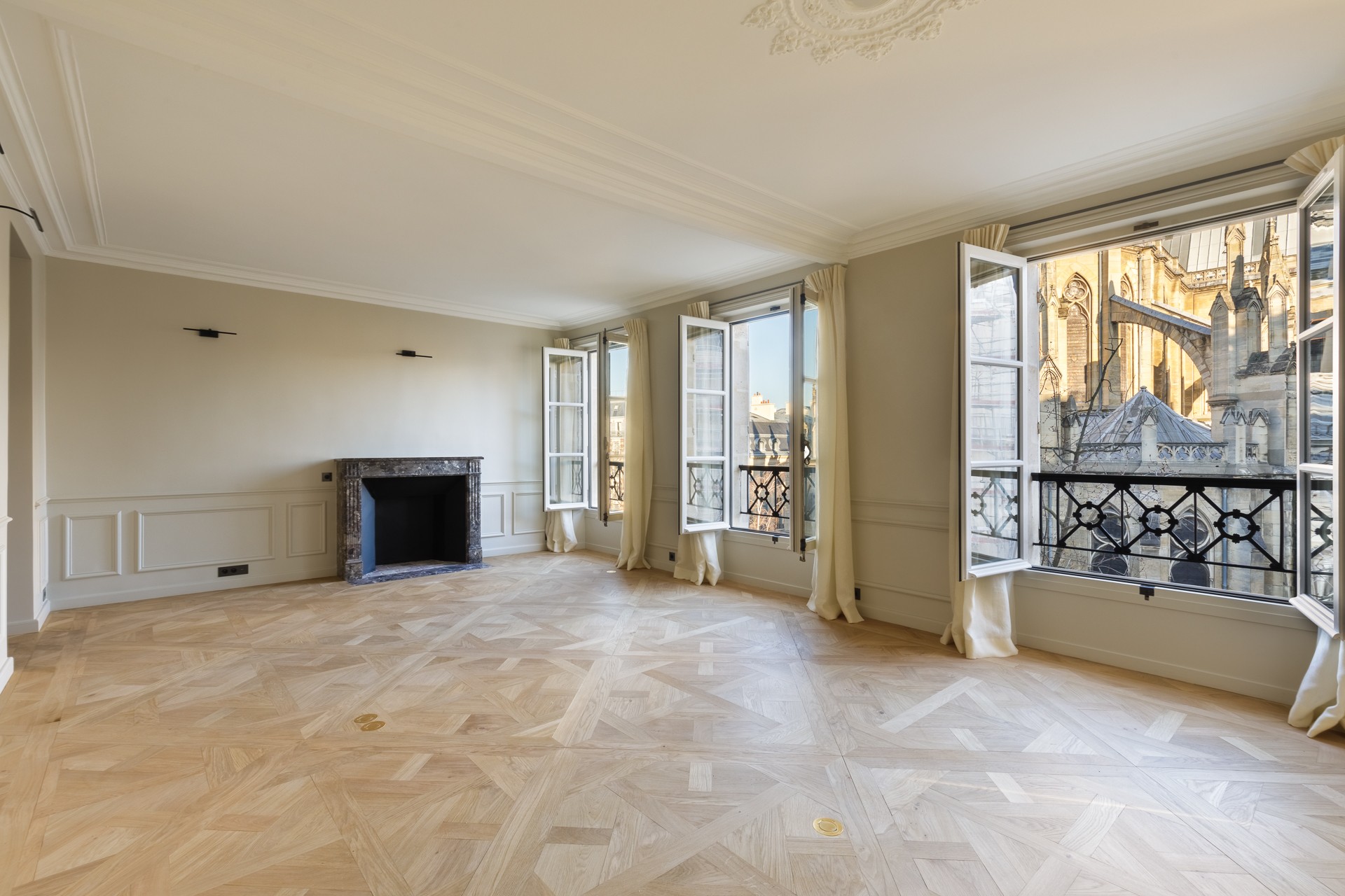 Interieur parisien vide cheminé parquet et vue église fenêtres ouvertes 