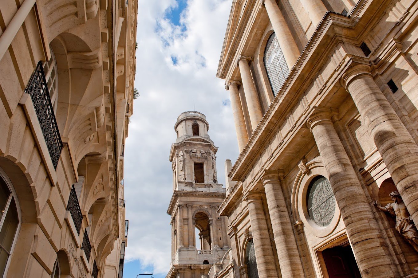 Vue sur des immeubles en pierre de taille assortis au clocher de l'église saint sulpice à paris