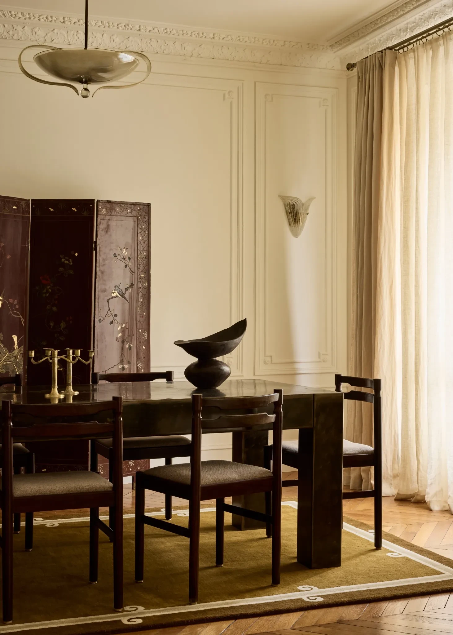 Salle à manger raffinée avec paravent asiatique, table en bois foncé, chaises contemporaines et décoration classique